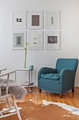 Armchair and side table on castors below gallery of pictures on living room wall