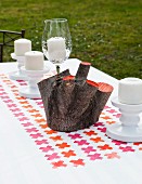 Painted wooden stump and candles on tablecloth printed with pink and orange crosses