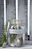 Silver spoons and rosemary in mason jar with welcome sign