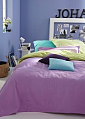 Gefärbte Kissenhüllen in verschiedenen Farben auf Bett mit violettem Plaid
