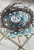 Bird food in enamel bowls and wreath of twigs on garden chair