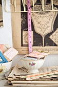 Old sewing utensils in bowl with floral motif on stack of papers