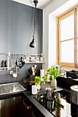 Dark kitchen with grey wall and utensils hung from wall-ounted bar