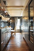 Elegant stainless steel kitchen counter with extractor hood and rustic wooden floor in elegant renovated interior