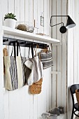 Hand-made linen bags hung from black hooks in cloakroom