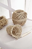 Crochet work, crochet needle and parcel string on white chair