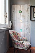 Floral armchair in front of retro reading lamps mounted on rustic wooden boards