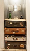 Various glass vessels on wooden surface on top of vintage suitcases stacked in niche