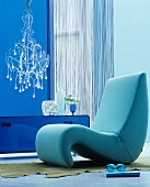 Organic easy chair in blue interior with modern chandelier