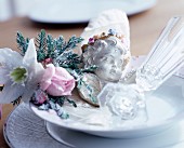 Place setting festively decorated with artificial flowers, cherub and Champagne glass
