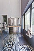 Modern stainless steel kitchen with cement-tiled floor and industrial windows