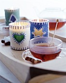 Tealight holders with felt covers and cup of tea with rock sugar swizzle stick