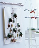 Advent calendar made from white felt with punched eyelets and small wrapped gifts hung from branch