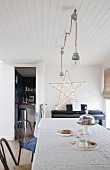 Large fairy-light star on wall in simple dining room