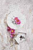 Easter eggs and pink primula flowers on plate next to tiny bird box