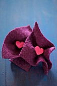 Small wooden hearts in squares of felt on blue surface