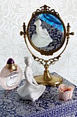 Feminine still-life arrangement of mirror, china figurine and perfume
