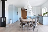 Essplatz mit grauen Retro Metallstühlen um runden Klassikertisch in blau-grauer Landhausküche