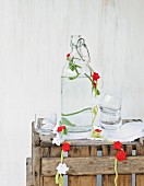 Garland of crocheted flowers draped around vintage glass bottle on rustic wooden crate