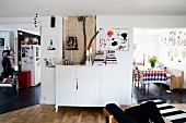White sideboard between open doorways leading into dining room and kitchen in open-plan interior
