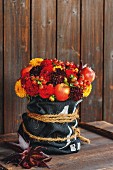 Autumnal flower arrangement in shades of red with dahlias, rose hips and apples