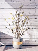 Concrete planter with branches in front of a white board wall