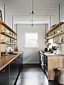 Black kitchen units with wooden worktops and suspended wall shelves