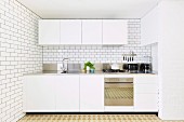 Schlichte weiße Einbauküche mit weißen Wandfliesen
