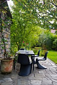 Black classic chairs and dining table on stone terrace outside Italian farmhouse