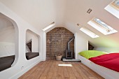 Modern alcoves and colourful cushions on integrated white benches below skylights in converted attic