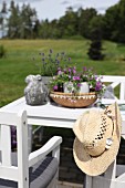 White wooden chairs and table on terrace with straw hat on backrest of chair