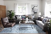 Leather armchair and sofa set around modern coffee table and patterned rug in rustic living room