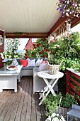 Comfortable corner sofa, coffee table, herbs, climbing roses and hanging baskets on veranda