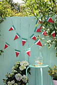 Hand-made bunting on green wooden fence in garden