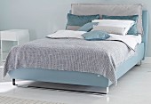 A boxspring bed in blue tones in a bedroom