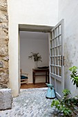 Terrace with stone floor and lattice door leading into hallway with console table