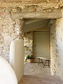 Rustic bench and potted geranium in entrance to stone house