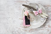 Hand-made place card made from black cardboard, pink felt and pink flower next to cutlery decorated with felt butterfly