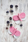 Pink and white, hand-made felt butterflies and blue-painted pine cones arranged on vintage wooden surface