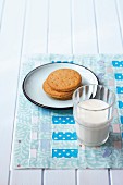 Glass of milk and plate of biscuits on place mat hand-made from woven strips of pastel fabrics