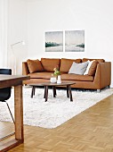 Nesting coffee tables and a brown leather sofa on a white flokati rug with landscape pictures in the background
