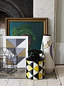 Still-life arrangement of retro vases, small wire house and picture in gilt frame