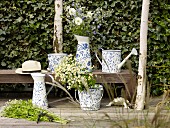 Jugs, watering can and bucket with rustic, floral patterns on terrace