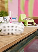 Refreshing drinks on modern outdoor side table on wooden deck next to pool