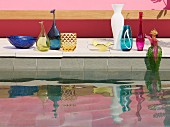 Collection of elegant vases on edge of pool reflected in water