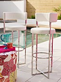 Modern bar stools with white leather covers and chrome frames on terrace next to pool