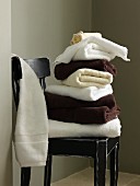 White an dark brown towels stacked on vintage wooden chair