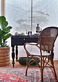 Antique desk and cane chair in front of bamboo roller blind
