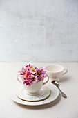 Weisses Tischgedeck dekoriert mit Blüten und Namenszug