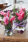 Romantic arrangements of cyclamen and sprigs of rosemary arranged in glass vases